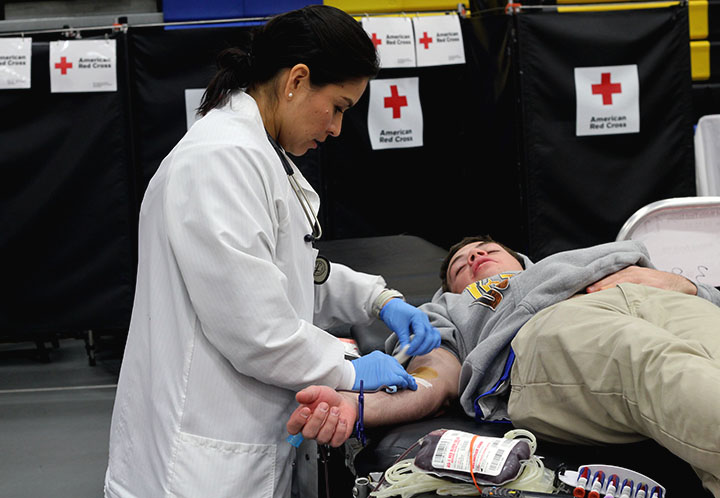 A Red Cross nurse bandages a student after donating blood. 