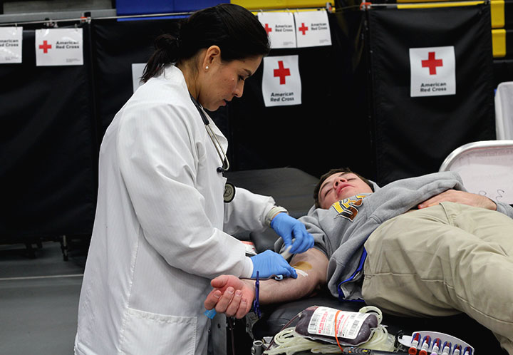 A Red Cross nurse bandages a student after donating blood.