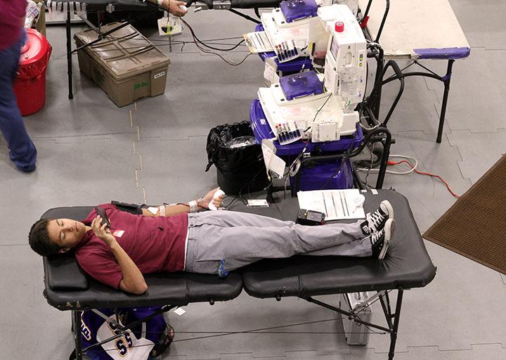 Bishop Amat student passes time on his phone as he waits to finish donating blood. 
