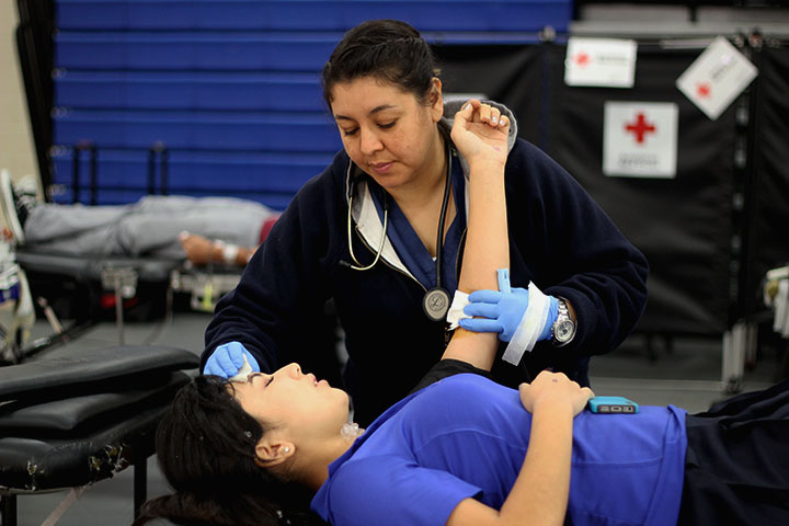 A Red Cross nurse applies pressure to a students arm after donating. 