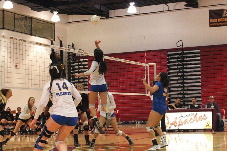 Varsity girls work together to get the ball over the net.