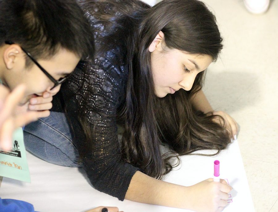 Participants decorate a football poster.