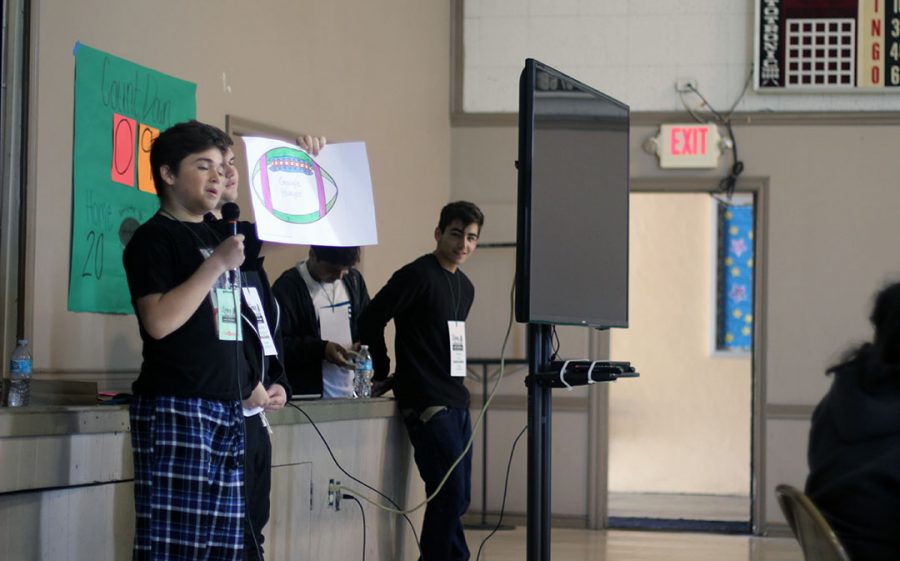 A student presents his groups football with ideas on how to end world hunger.