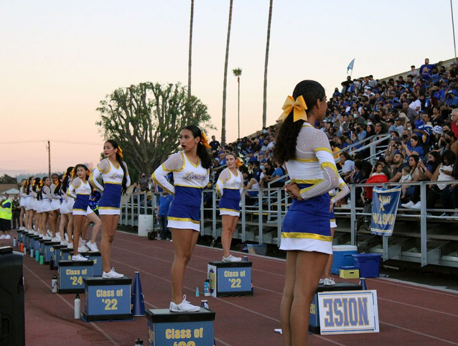 The cheerleaders turning to watch an exciting play on the field. 