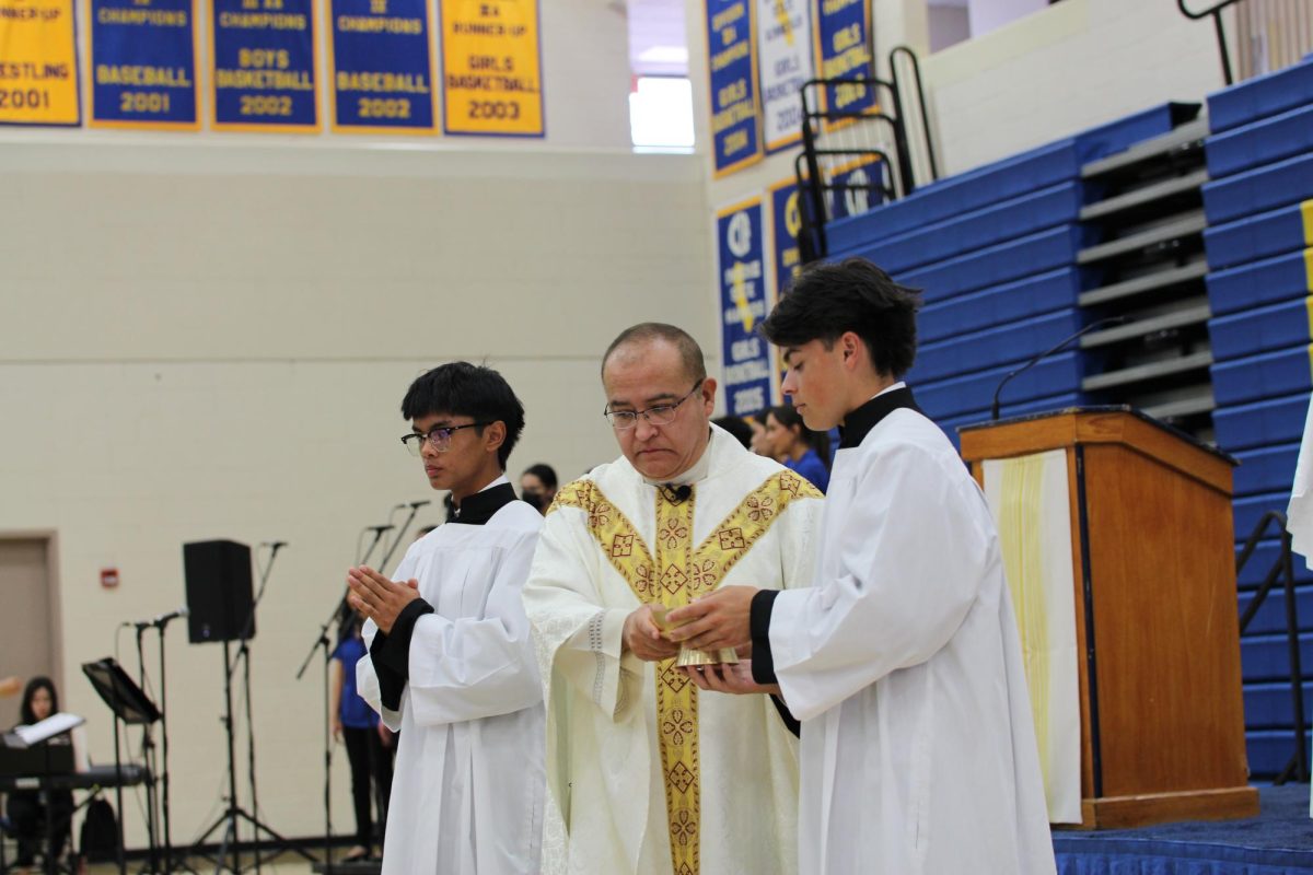 Father John hands the body of christ to an Altar Server.